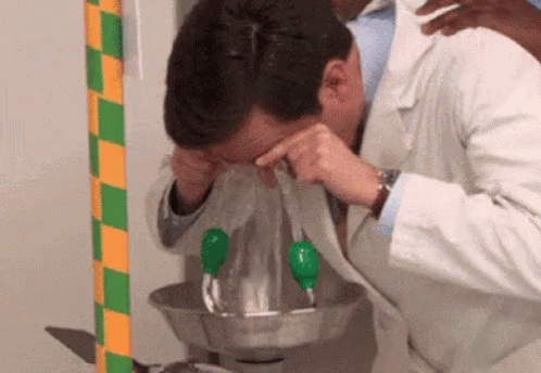 A Man In A Lab Coat Is Washing His Eyes In A Bowl Of Water GIF