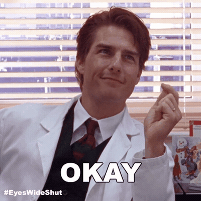 A Man In A Lab Coat Says Okay In Front Of Blinds GIF