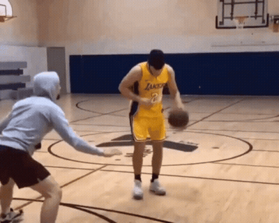 A Man In A Lakers Jersey Dribbles A Basketball On A Court GIF