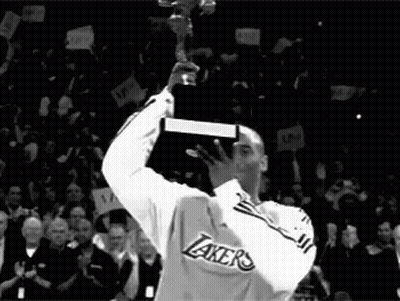 A Man In A Lakers Jersey Holds Up A Trophy In Front Of A Crowd GIF