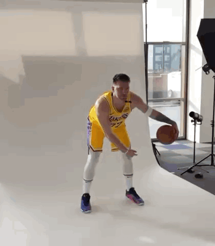 A Man In A Lakers Jersey Is Holding A Basketball In A Studio . GIF