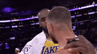 A Man In A Lakers Jersey Is Hugging Another Man In A White Shirt GIF