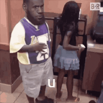 A Man In A Lakers Jersey Is Standing Next To A Woman . GIF