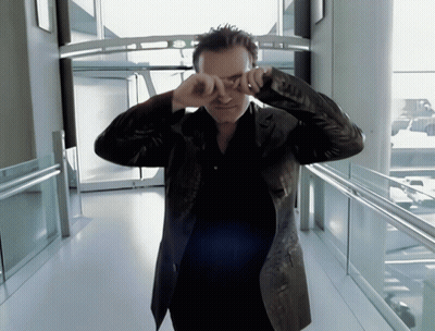 A Man In A Leather Jacket Is Covering His Eyes With His Hands GIF