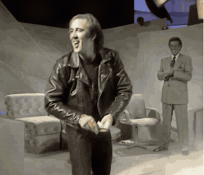 A Man In A Leather Jacket Is Dancing In Front Of A Man In A Suit And Tie GIF