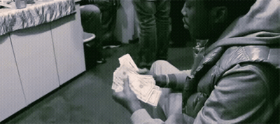 A Man In A Leather Jacket Is Holding A Bunch Of Money In His Hands GIF