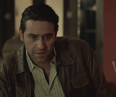 A Man In A Leather Jacket Is Holding A Glass Of Wine GIF