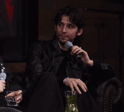 A Man In A Leather Jacket Is Holding A Microphone GIF