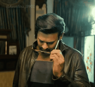 A Man In A Leather Jacket Is Holding A Pair Of Glasses . GIF