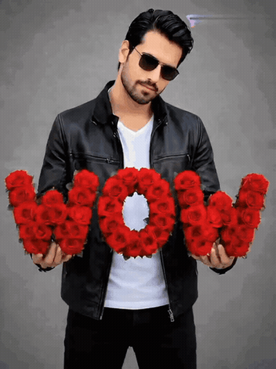 A Man In A Leather Jacket Is Holding A Wreath Of Red Roses That Spell Out The Word Wow GIF