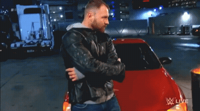 A Man In A Leather Jacket Is Hugging A Red Car In Front Of A Fire Barrel That Says Wwe Live GIF