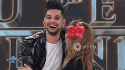 A Man In A Leather Jacket Is Laughing With A Woman In A Red Bow In Her Hair .. GIF