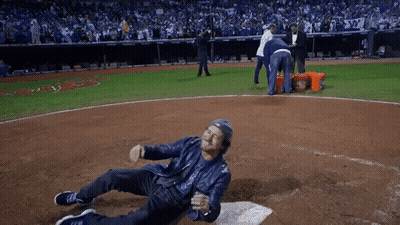 A Man In A Leather Jacket Is Laying On The Ground On A Baseball Field GIF