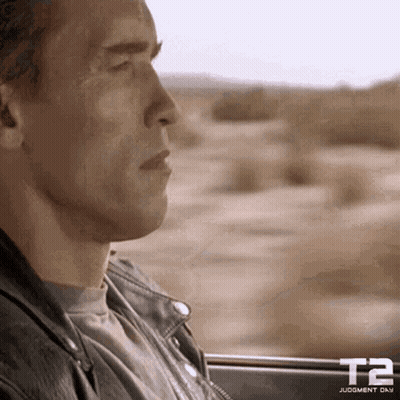 A Man In A Leather Jacket Is Looking Out Of A Car Window GIF