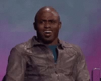 A Man In A Leather Jacket Is Making A Funny Face While Sitting In Front Of A Purple Background . GIF