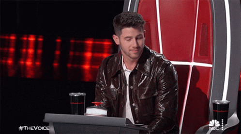 A Man In A Leather Jacket Is Sitting In A Chair With A Laptop In Front Of Him And The Words #Thevoice On The Bottom GIF