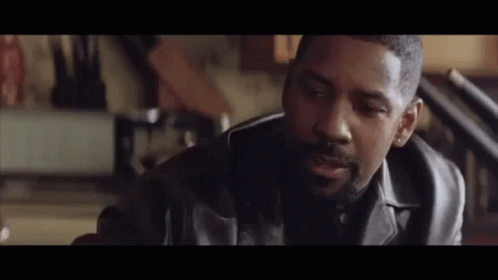 A Man In A Leather Jacket Is Sitting In A Room Talking To Another Man . GIF