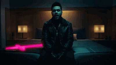 A Man In A Leather Jacket Is Sitting On A Bed In A Dark Room GIF
