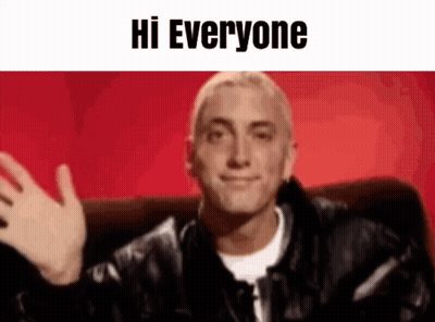A Man In A Leather Jacket Is Sitting On A Couch And Waving His Hand . GIF
