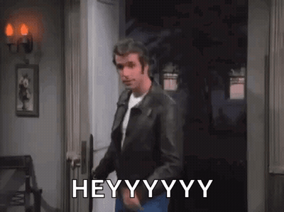 A Man In A Leather Jacket Is Standing In A Doorway And Says Hey . GIF