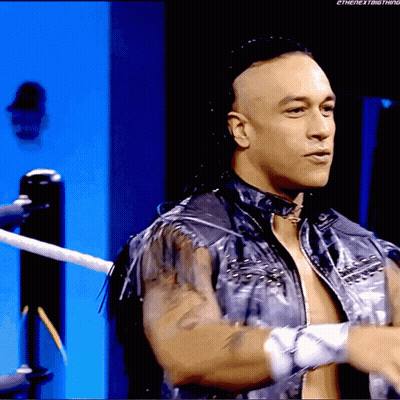 A Man In A Leather Jacket Is Standing In A Wrestling Ring GIF