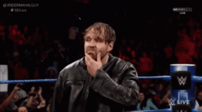 A Man In A Leather Jacket Is Standing In A Wrestling Ring With His Hand To His Chin . GIF