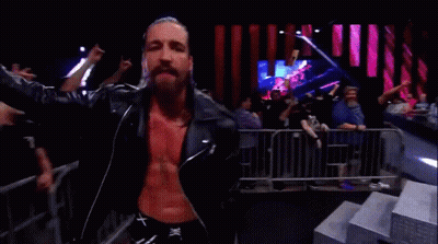 A Man In A Leather Jacket Is Standing In Front Of A Crowd Of People . GIF