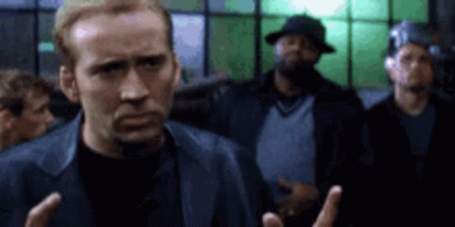 A Man In A Leather Jacket Is Standing In Front Of A Group Of Men In A Room . GIF