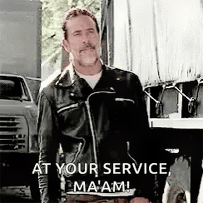 A Man In A Leather Jacket Is Standing In Front Of A Truck With The Words `` At Your Service , Ma 'Am '' . GIF