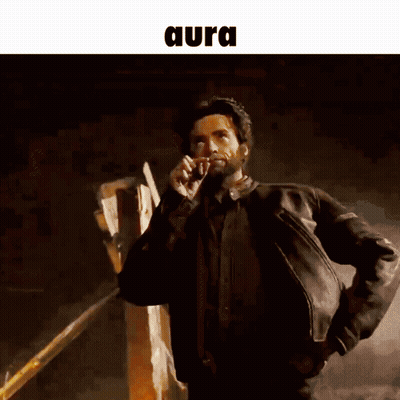 A Man In A Leather Jacket Is Talking On A Cell Phone And The Word Aura Is Above Him GIF