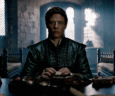 A Man In A Leather Jacket Sits At A Table Holding A Piece Of Paper GIF