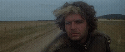 A Man In A Leather Jacket Stands In A Field GIF