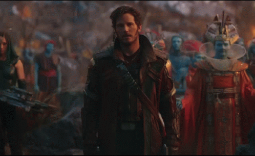 A Man In A Leather Jacket Stands In Front Of A Crowd Of People GIF