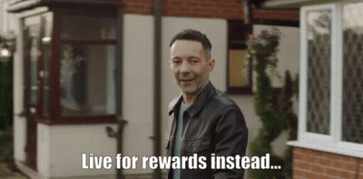 A Man In A Leather Jacket Stands In Front Of A House With The Words Live For Rewards Instead Written Below Him GIF