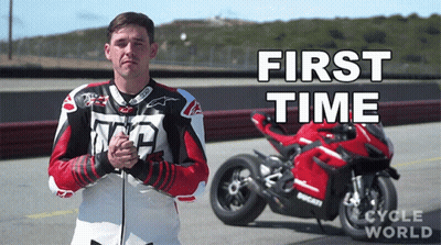 A Man In A Leather Jacket Stands In Front Of A Red Motorcycle That Says First Time GIF