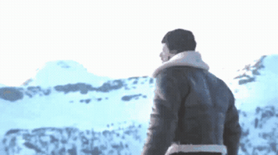 A Man In A Leather Jacket Stands In Front Of A Snowy Landscape GIF