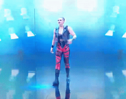 A Man In A Leather Vest And Red Pants Is Dancing In Front Of A Blue Background GIF