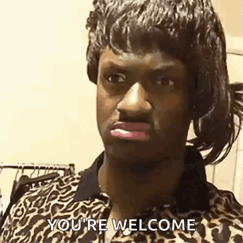 A Man In A Leopard Print Shirt Is Saying `` You 'Re Welcome '' While Wearing A Wig . GIF