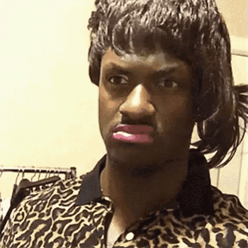 A Man In A Leopard Print Shirt Is Wearing A Wig And Pink Lipstick . GIF