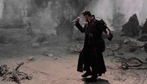 A Man In A Long Black Coat Is Holding A Sword GIF