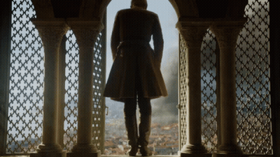 A Man In A Long Coat Is Standing In Front Of A Window GIF