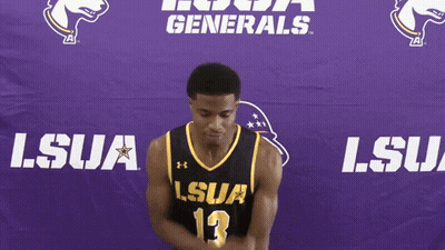 A Man In A Lsua Jersey Stands In Front Of A Purple Banner GIF