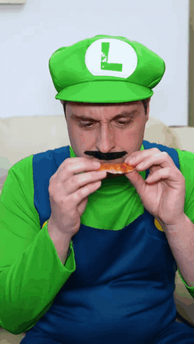 A Man In A Luigi Costume Eating A Piece Of Pizza GIF