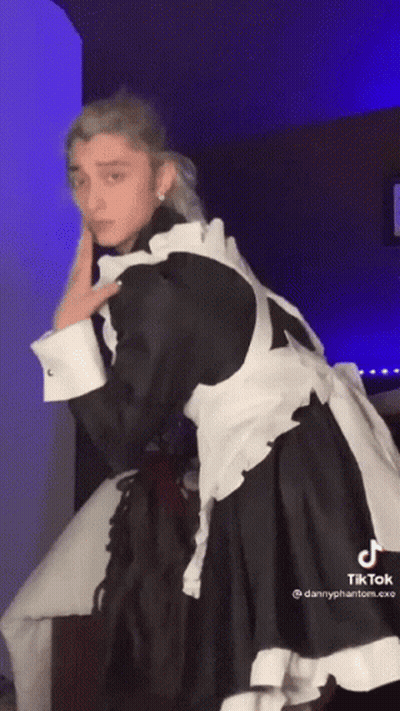 A Man In A Maid Costume Is Dancing In A Room With A Blue Light Behind Him . GIF
