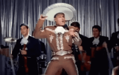 A Man In A Mariachi Outfit And Sombrero Is Singing Into A Microphone . GIF