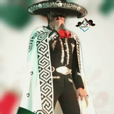 A Man In A Mariachi Outfit Is Holding A Microphone And Wearing A Sombrero GIF