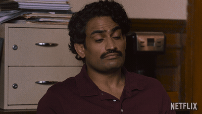 A Man In A Maroon Shirt Is Sitting In Front Of A Netflix Logo GIF