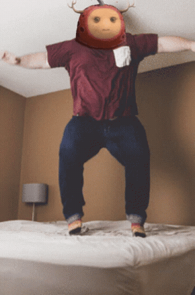 A Man In A Maroon Shirt Jumps On A Bed GIF