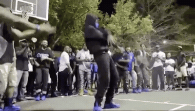 A Man In A Mask Is Dancing On A Basketball Court In Front Of A Crowd Of People . GIF