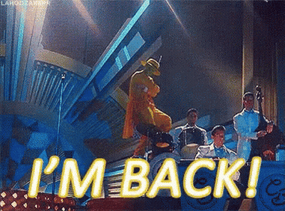 A Man In A Mask Is Dancing On A Stage With A Band And The Words I 'M Back GIF